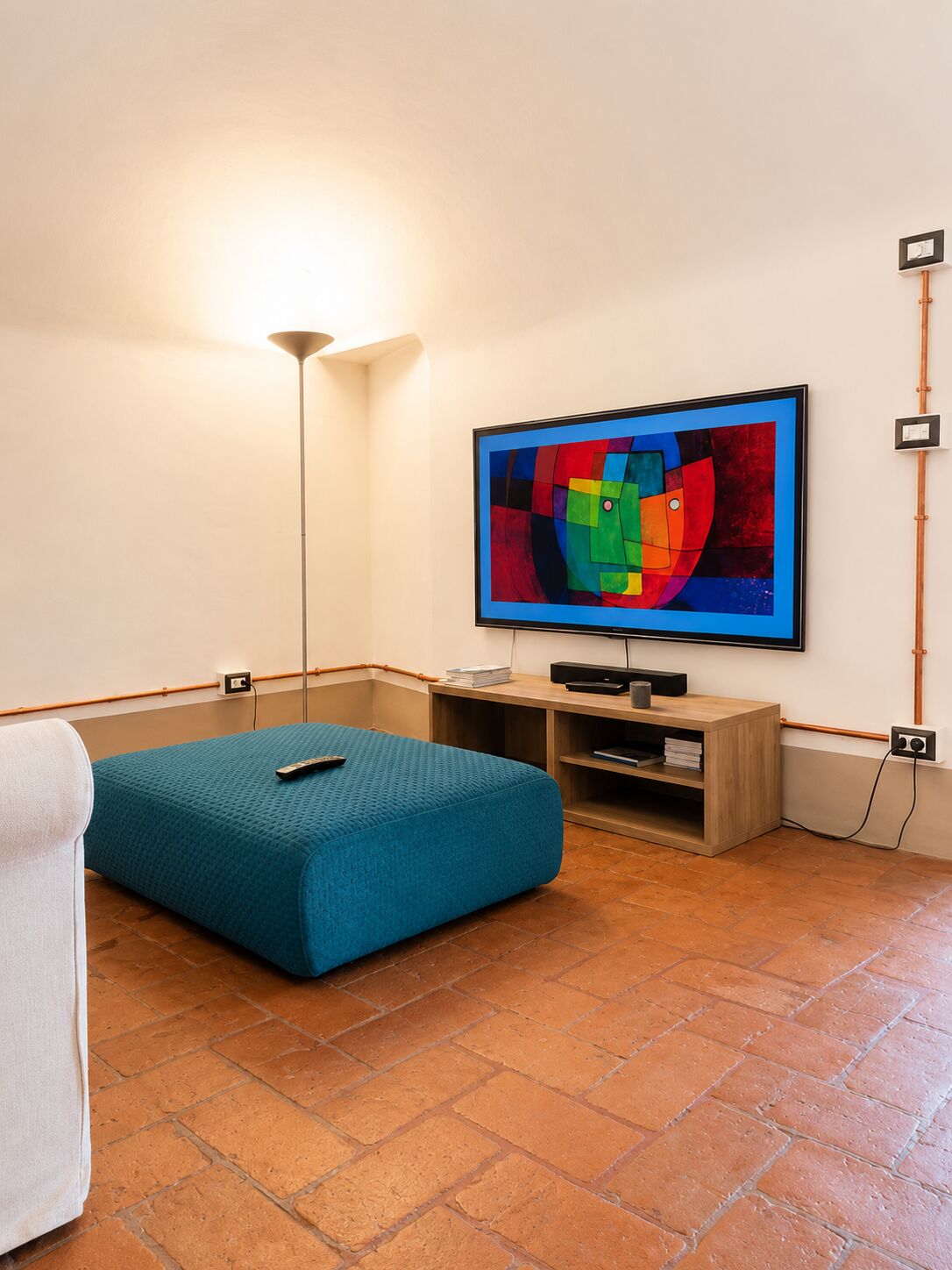 Angolo TV con pouf blu e schermo da 65 pollici