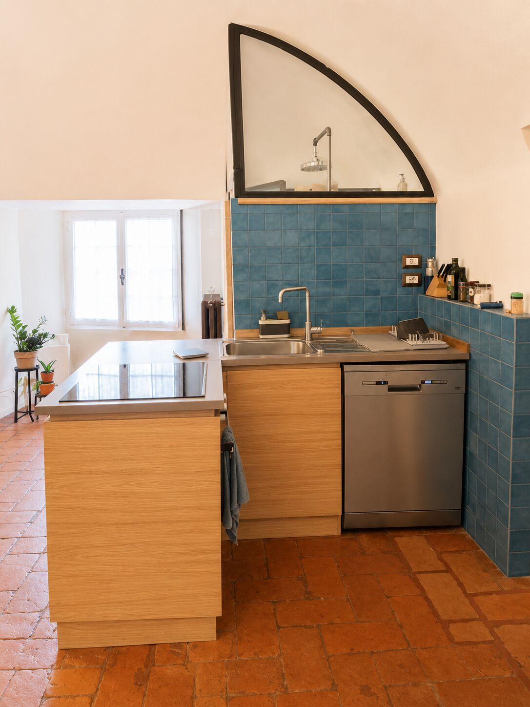 La cucina con piastrelle blu petrolio e la finestra ad arco
